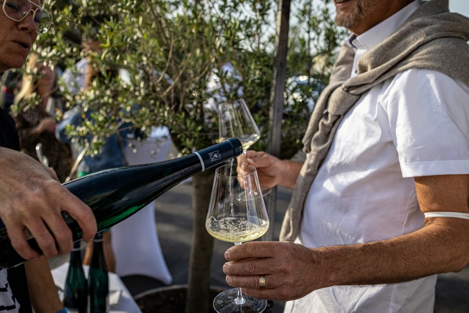 A rep pouring white wine for a guest
