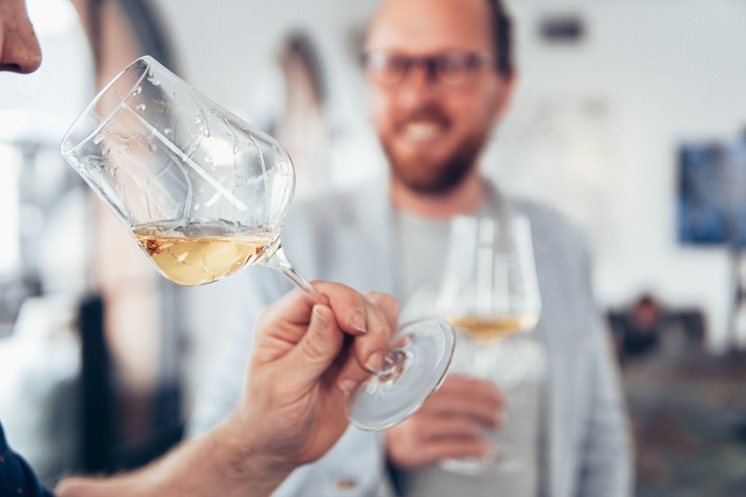 A taster swirling a glass of white wine